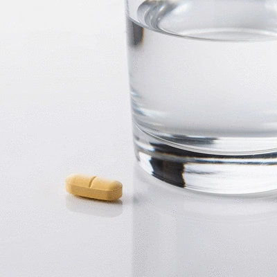 Person taking an antihistamine pill, with a glass of water on a clean background. No text, no words, no typography, 8K.